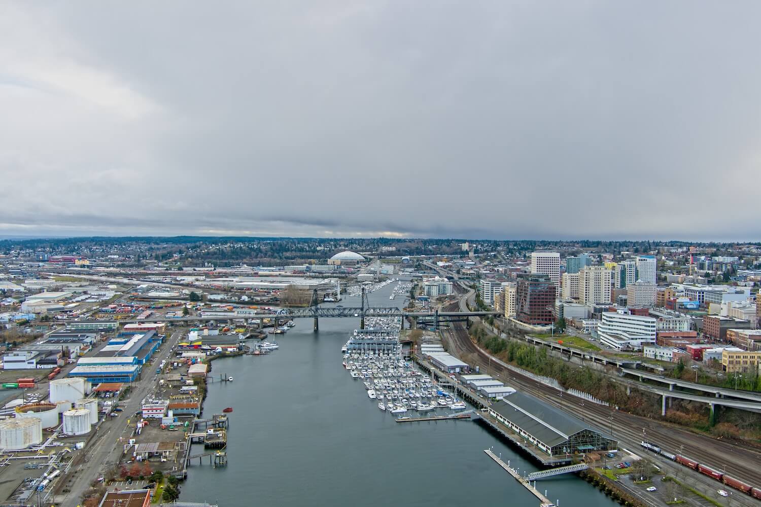 Aerial view of a waterfront city with marinas, industrial buildings, bridges, and downtown high-rises under a cloudy sky. Plumbers in Black Diamond, WA